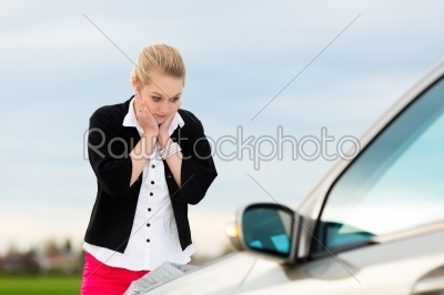 Young woman with map on car being lost