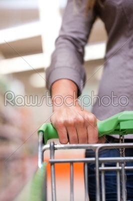 Young woman with pushcart in supermarket