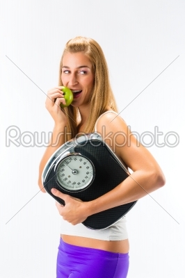 Young woman with scale under her arm and apple