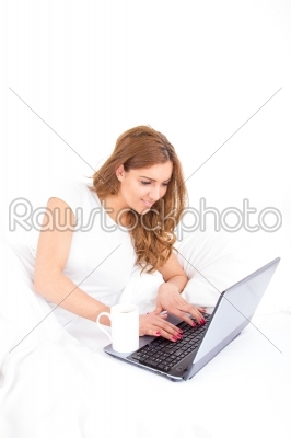 angle view of woman using laptop computer in bed