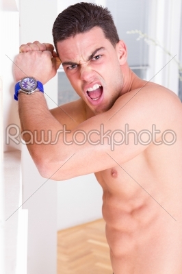 angry half naked man having problems and hitting the wall