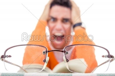 angry young man with glasses in sweater reading book