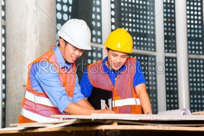 Asian architect and supervisor on building site 