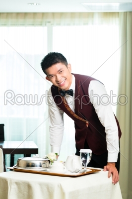 Asian Chinese room service waiter serving food in hotel