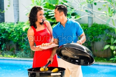 Asian couple having barbecue at the pool 