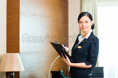 Asian _exec_utive housekeeper controlling hotel room