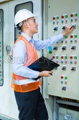 Asian technician at panel on construction site
