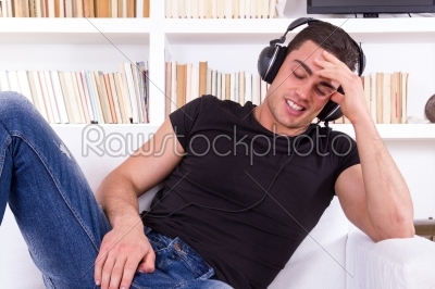 asual man with headphones relaxing on the sofa at his home