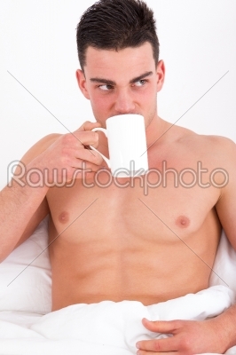 attractive man in bed drinking coffee
