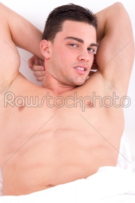 attractive man lying in his bed smiling and seducing