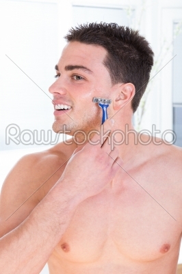 attractive man shaving his face holding razor