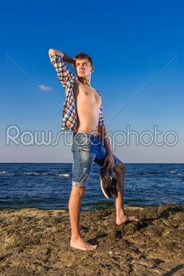 Attractive young fashion sexy man on rock near the sea water wit