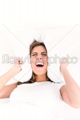 Beautiful business woman lying in bed and covering her ears with