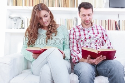 Beautiful loving casual couple reading a book on the sofa