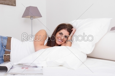 beautiful young woman lying on the bed with magazine beside her