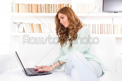 beautiful young woman typing on laptop computer keyboard at home