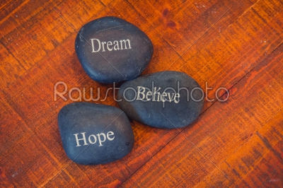 Black inspirational pebble stones with the words Dream, Believe 