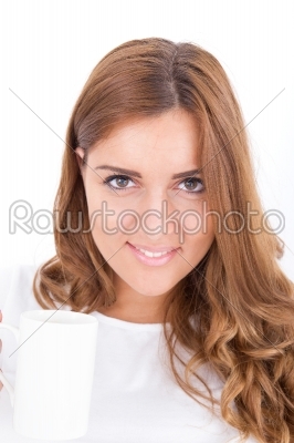 brunette woman drinking beverage from a cup in bright bedroom