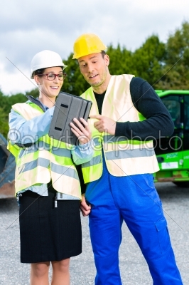 builders with blueprint on construction site