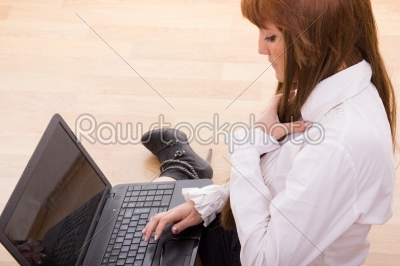 business woman sitting on the floor typing on laptop keyboard