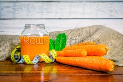 Carrot juice on a table with measure tape