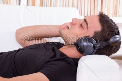 casual man lying on couch listening to music