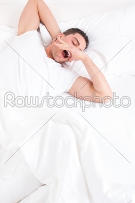 casual man waking up in the bedroom and stretches with yawning i