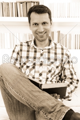 Casual unshaven handsome man relaxing at home on a sofa in the l