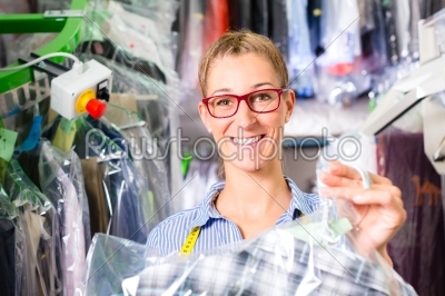 Cleaner in laundry shop checking clean clothes