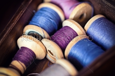 Collection of blue spools threads  arranged in a grunge wooden box