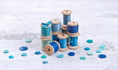 Collection of spools  threads in blue, aqua colors arranged on a white wooden background