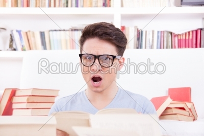confused student with glasses  surrounded by books