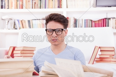 confused student with glasses studying surrounded by books