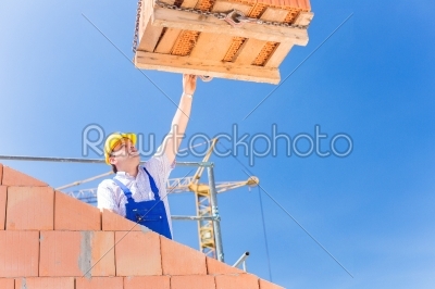 Construction site worker building house with crane