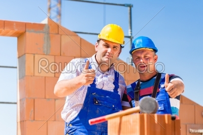 Construction site workers building walls on house