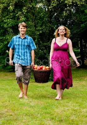 Couple carrying basket with apples