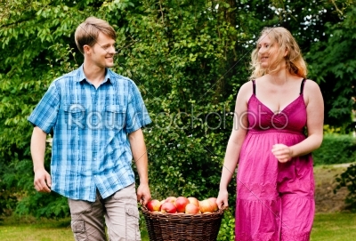 Couple carrying basket with apples