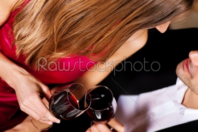 Couple drinking red wine clinking glasses