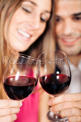 Couple drinking red wine clinking glasses