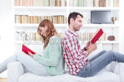 couple is seated together on a couch back to back