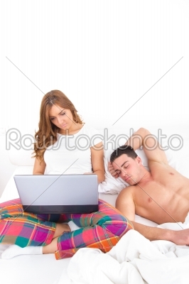 Couple with laptop computer in bed