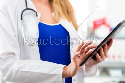 Doctor in clinic reading digital file on tablet computer
