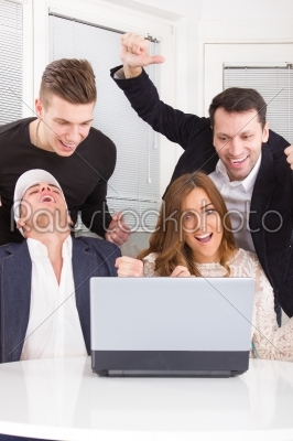 excited happy group of friends winning online using laptop