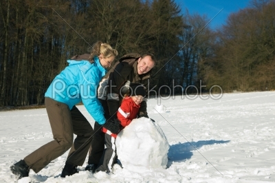 Family with kids building snowman