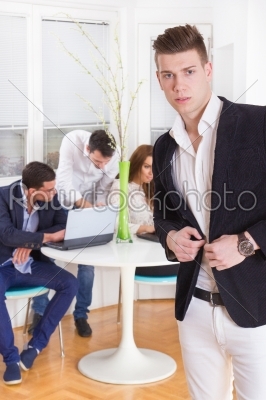 fashion man in a business atmosphere with colleagues behind him