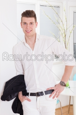 fashion young man standing with his hands in his pockets and smi