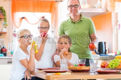 Father and daughters in kitchen eating healthy