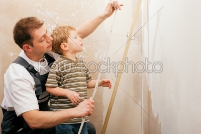 Father and son measuring dry wall