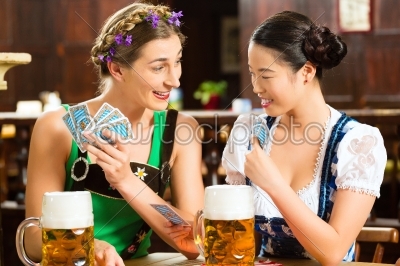 friends drinking beer in Bavarian pub playing cards