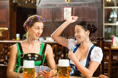 friends drinking beer in Bavarian pub playing cards